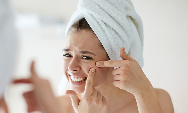 A woman with a towel on her head is looking at the camera.