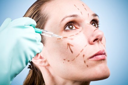 A woman getting her face waxed by a doctor.