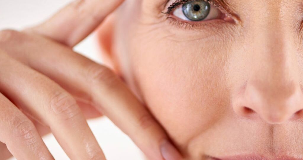 A woman with blue eyes touching her face.