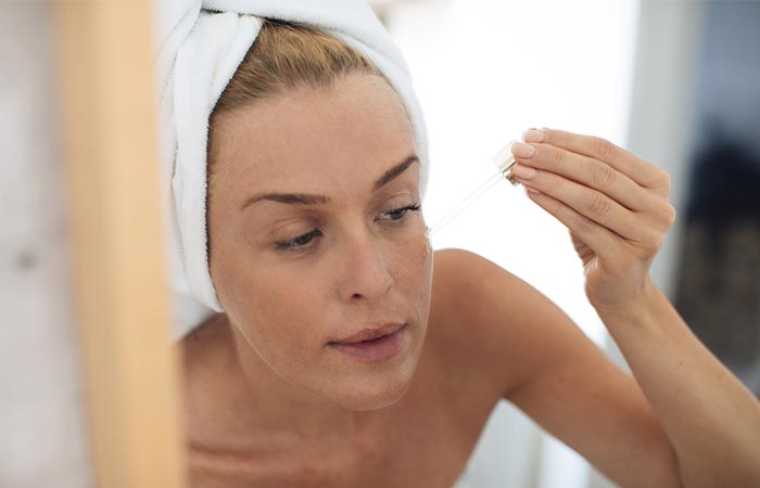 A woman with a towel on her head is looking in the mirror.